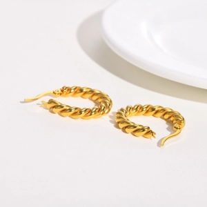 Close-up of gold twisted croissant hoop earrings with a polished metallic finish