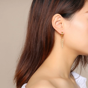 Golden geometric triangle drop earrings with hollow circles on a female model