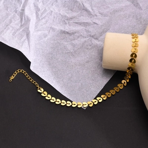 Close-up of golden heart-shaped anklet with lobster clasp on a modern geometric display