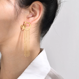 Detail view of golden stainless steel butterfly tassel earrings worn by a model
