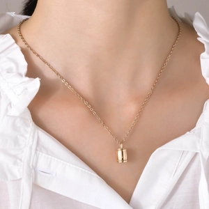 Pendentif urne cylindrique doré poli sur collier porté par un mannequin femme