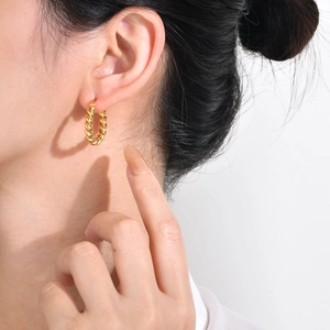 Minimalist gold twisted hoop earrings in stainless steel worn by a model for fashion