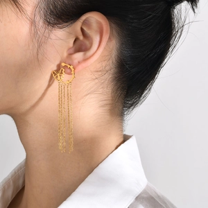 Detailed view of a gold butterfly tassel earring with delicate metal chains on model