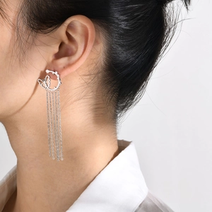 Silver stainless steel tassel drop earrings with butterfly charm worn by a model