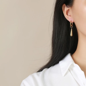 Minimalist gold teardrop earrings in polished stainless steel for women on a model