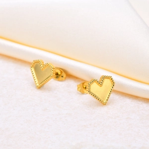 Detailed close-up of golden heart earrings with elegant milgrain beaded edges