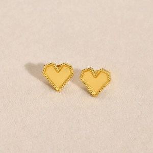 Macro detail of gold heart earrings featuring delicate milgrain beaded edges and polished finish
