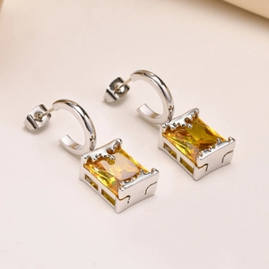 Macro view of silver steel earrings featuring radiant rectangular yellow cubic zirconia