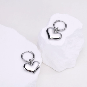 Vue macro des boucles d'oreilles cœur en argent sur pierres avec finition polie