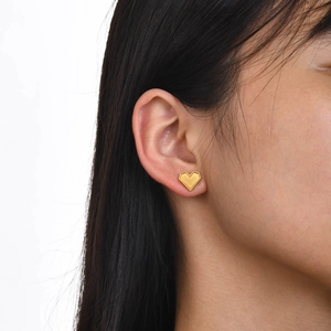 Close-up of gold heart stud earring with beaded edge detail worn by a female model