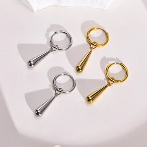 Polished gold and silver stainless steel teardrop earrings on a modern stone display