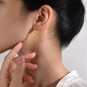 Gros plan d'un mannequin portant des boucles d'oreilles chaînes dorées en acier inoxydable