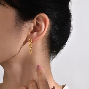 Boucles d'oreilles minimalistes en titane doré portées par un mannequin en vue de profil