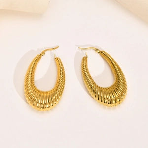 Macro detail of gold chunky hoop earrings featuring a ribbed croissant texture finish