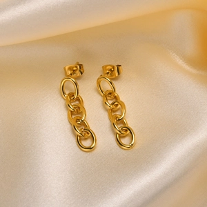 Gros plan de boucles d'oreilles chaînes en acier titane doré sur satin champagne