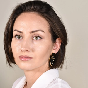Detail of geometric black enamel triangle drop earrings with gold edges on a model