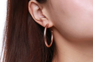 Gros plan d'une créole en titane or rose de 42mm portée avec finition miroir