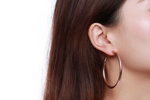 Gros plan d'un mannequin portant de grandes créoles de 42mm en acier titane doré rose poli