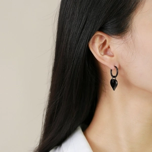 Gros plan d'un mannequin portant des boucles d'oreilles cœur noires au fini métallique