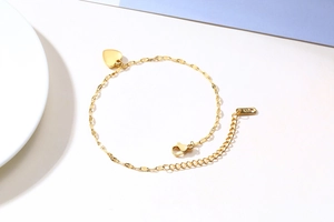 Macro detail of golden heart pendant with K18 stamp on polished stainless steel chain
