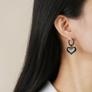 Détail d'un pendentif cœur noir porté par un mannequin sur un fond lumineux et naturel