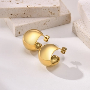 Polierte goldene C-förmige Creolen auf strukturiertem Stein für einen modernen Look