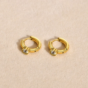 Detailed view of C-shaped 18K gold plated earrings with sparkling zircon crystals