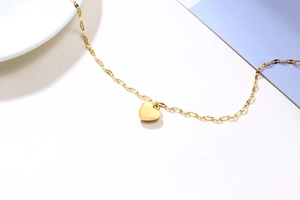 Detailed close-up of a polished gold heart pendant with a delicate twisted link chain