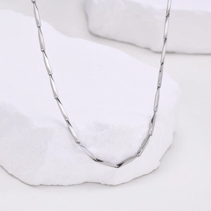 Detailed view of silver rectangular link chain resting on a white textured stone