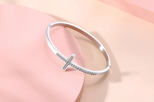 Détail d'un bracelet en acier inoxydable argenté avec croix sertie de micro-diamants
