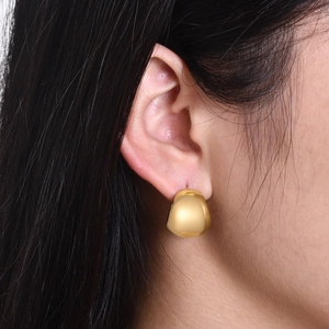 Nahaufnahme von goldenem Tropfen-Ohrring in C-Form, am Model im minimalistischen Stil
