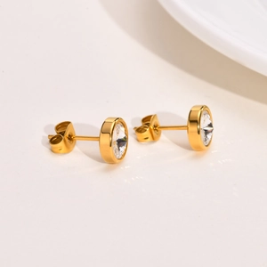 Detailed close-up of gold-plated zircon stud earrings with classic butterfly backings