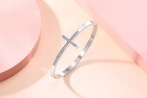 Gros plan détaillé d'un bracelet jonc en acier argenté avec croix sertie de cristaux