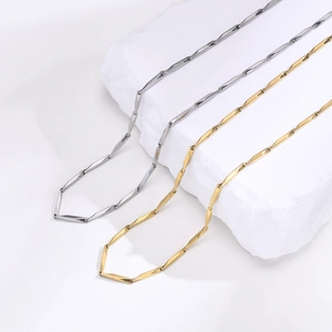 Detail of 18k gold and silver stainless steel bamboo link chains on white stone