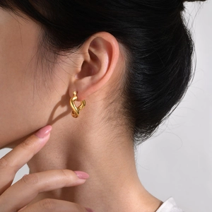 Orecchini a cuore attorcigliati irregolari con finitura dorata lucida su modella donna