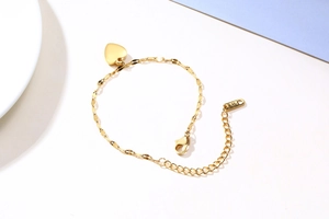 Detail of gold heart pendant bracelet with K18 engraving and adjustable sequin chain