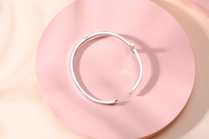 Détail du bracelet jonc ouvert en forme de T en acier inoxydable argenté sur socle rose