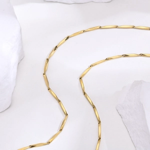 Detailed view of 18k gold plated stainless steel geometric chain necklace on stone