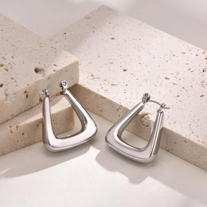 Minimalist hollow U-shaped stainless steel earrings on elegant beige travertine stone