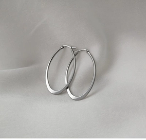 Detailed macro shot of large polished silver oval hoop earrings with a sleek minimalist design