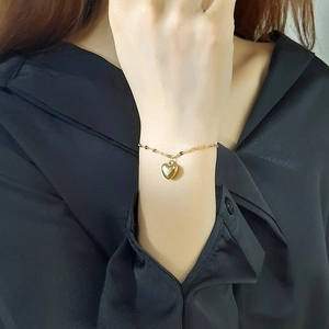 Close-up of a gold heart charm bracelet on wrist highlighting the polished metallic finish