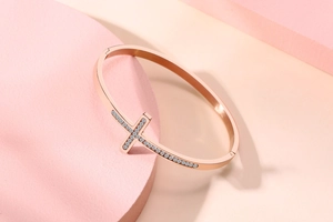 Détail macro du bracelet croix en or rose avec des pierres en zircone cubique scintillantes