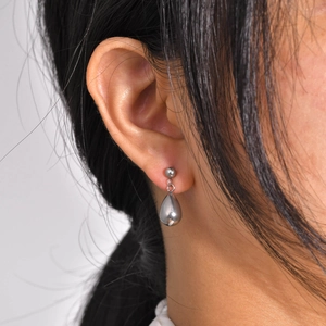 Polished silver stainless steel water drop earrings worn by a model in a close-up view