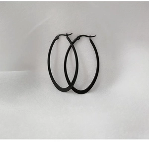 Detail view of large oval hoop earrings in matte black finish on soft white fabric