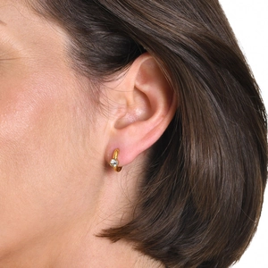 Macro shot of gold plated stainless steel hoop earring with a single clear zircon on ear