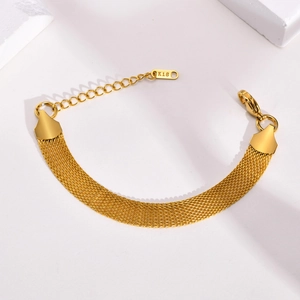 Macro detail of golden mesh chain bracelet with K18 tag and secure lobster clasp closure