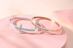 Détail de joncs croix en argent et or rose avec cristaux sur présentoir rose