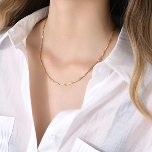 Detailed close-up of 18k gold-plated cylinder link necklace on model with white shirt