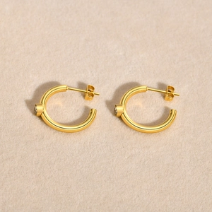 Detailed view of C-shaped 18K gold plated earrings with sparkling zircon on felt