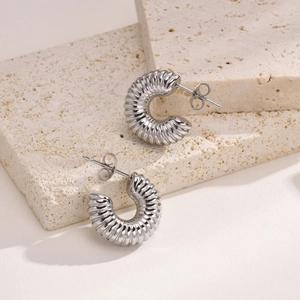 Nahaufnahme silberner hohler C-Ohrringe mit Spiralstruktur und Schmetterlingsverschluss-Details